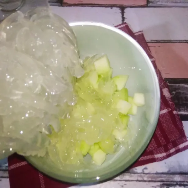 Siapkan mangkuk besar, masukkan potongan buah melon, serutan nutrijell kelapa dan biji selasih.