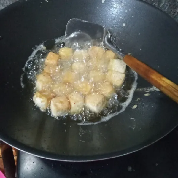 Masukkan tahu ke dalam minyak goreng, biarkan hingga berkulit lalu tuang adonan tepung menggunakan tangan dengan diputar-putar. 
Goreng hingga matang.