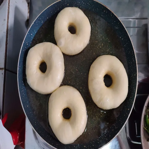 Panaskan minyak goreng, kemudian buat bolongan pada tengah donat, lalu goreng donat dengan api kecil hingga bagian bawah berwarna golden brown, kemudian balikkan. 
Cukup 1 kali balik saja. 
Jika kedua sisi donat sudah matang, angkat dan tiriskan minyaknya. 
Lalu biarkan hingga dingin.