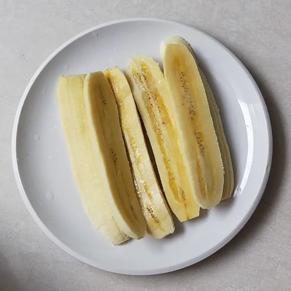 Belah pisang menjadi dua bagian lalu sisihkan.