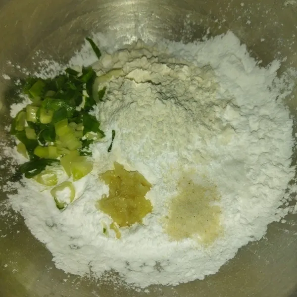 Siapkan wadah, masukkan tepung sagu, tepung terigu, daun bawang, bawang putih halus, garam dan kaldu bubuk.
