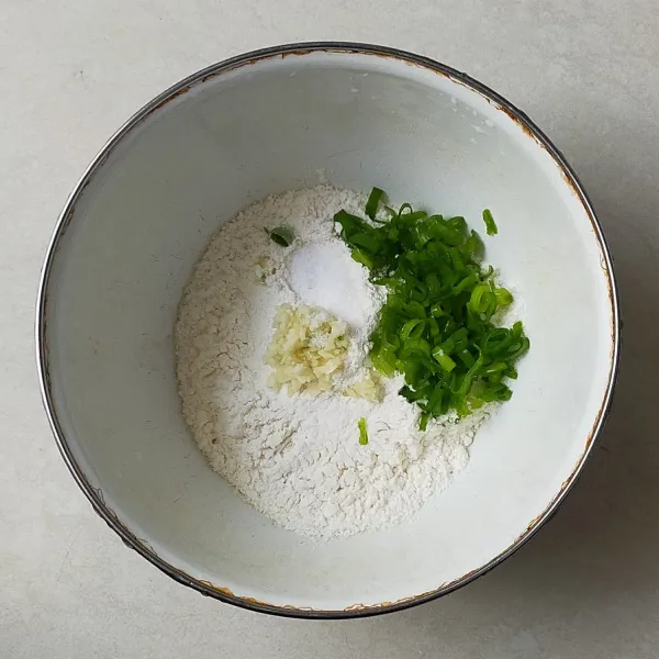 Dalam baskom campurkan tepung terigu,daun bawang, bawang putih halus dan garam.
