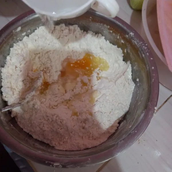 Masukkan telur juga air sedikit sedikit sampai adonan menyatu.