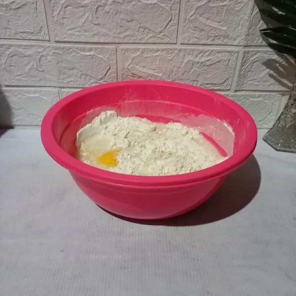 Siapkan bowl. Masukkan tepung, gula, dan ragi. Aduk-aduk. Kemudian masukkan kuning telur dan air. Uleni sebentar.