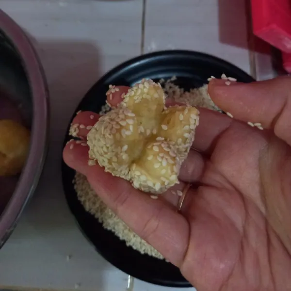 Celupkan adonan ke dalam air, lalu baluri dengan wijen sampai menempel, gunting bagian ujung adonan menjadi 4 bagian menyerupai bunga.