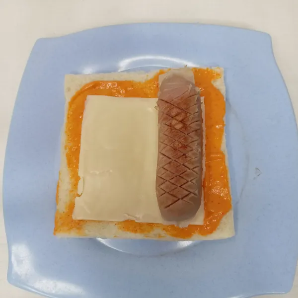 Pipihkan roti tawar. 
Oles mayo. 
Beri keju dan sosis.