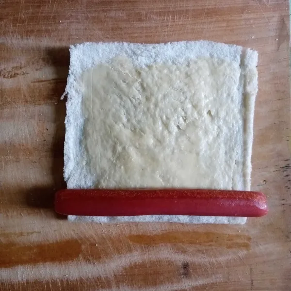 Oles roti dengan margarin, beri sosis lalu gulung perlahan dan sematkan dengan tusuk gigi agar tidak terlepas.