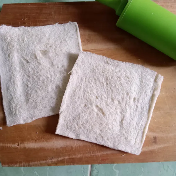 Gilas roti tawar dengan menggunakan rolling pin.