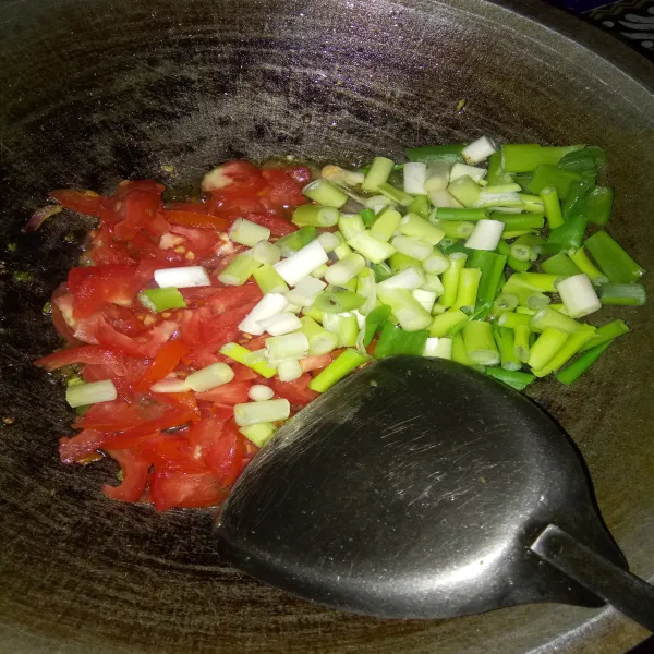 Tambahkan daun bawang dan tomat,  tumis hingga sedikit layu.