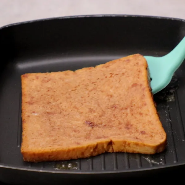 Lelehkan mentega di atas frying pan, panggang roti hingga kecoklatan di kedua sisinya.
