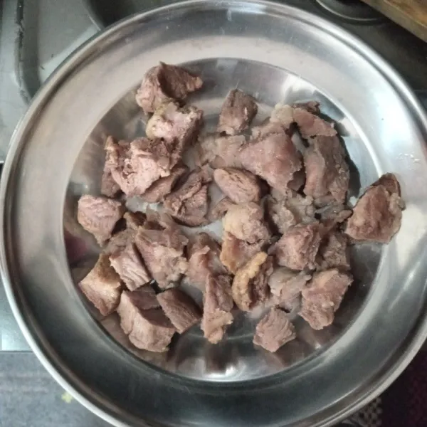 Cuci daging sapi, rebus hingga mendidih saja lalu angkat dan buang air kotornya, kemudian potong dadu, sisihkan.