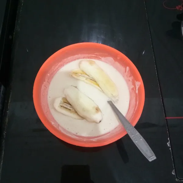 Lalu celupkan pisang ke dalam adonan tepung terigu. Baluri hingga rata.