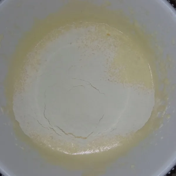 Tambahkan tepung terigu sambil disaring, kemudian kocok sampai tercampur rata.
