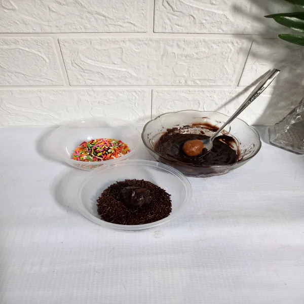 Celupkan bola-bola biskuit ke dalam coklat leleh. 
Kemudian lumuri dengan meses. 
Lakukan sampai selesai.