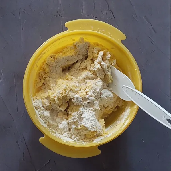 Tambahkan tepung terigu, tepung maizena dan susu bubuk sambil diayak, aduk rata dengan spatula.