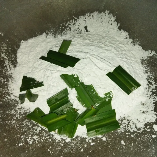 Sangrai tepung sagu dengan diberi potongan daun pandan.