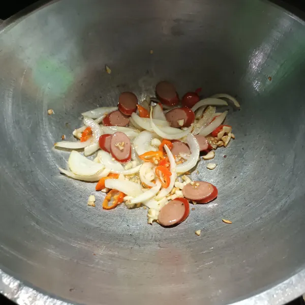 Panaskan minyak, lalu tumis bawang putih dan bawang bombay sampai harum. 
Lalu masukkan sosis dan cabe. 
Aduk.