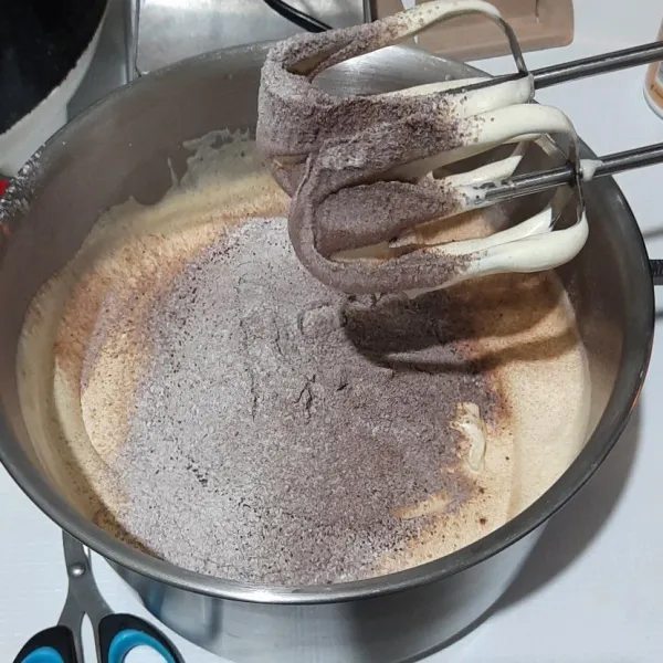 Tambahkan tepung dan coklat bubuk sambil diayak lalu kocok kembali.