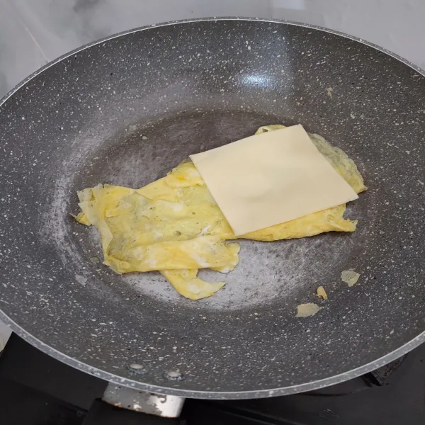 Goreng telur satu per satu dengan sedikit margarine, lalu di tengahnya letak keju slice selembar. Lipat dan masak hingga sedikit kecoklatan. Sisihkan.