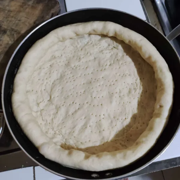 Siapkan teflon dan bentuk adonan pizzanya. Tusuk-tusuk memakai garpu bagian tengah pizzanya. Untuk pinggirannya tambahkan potongan keju mozzarella.