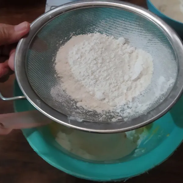 Dalam wadah yang lain campur tepung terigu, tepung maizena dan susu bubuk. 
Lalu ayakkan di atas campuran margarin.