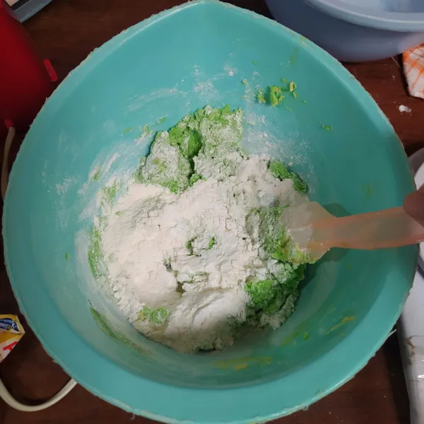 Ayak tepung terigu, tepung maizena, susu bubuk dan vanili. 
Masukkan ke dalam campuran margarin. Aduk dengan spatula.