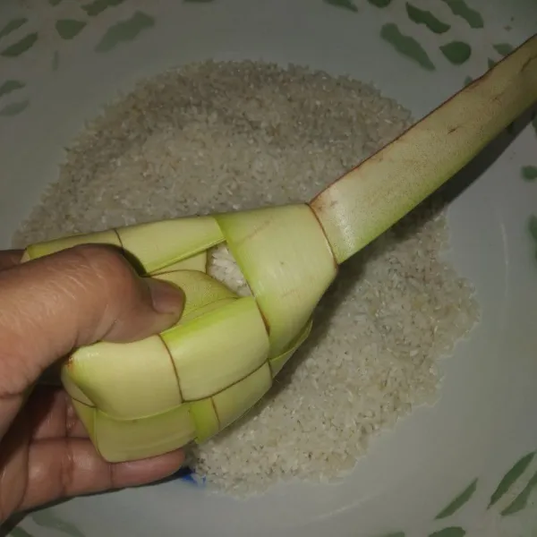 Lalu beri garam, aduk merata dan isi cangkang ketupat dengan beras sampai terisi setengah.