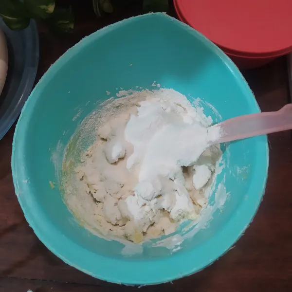 Dalam wadah yang lain campur tepung terigu, tepung maizena dan susu bubuk. 
Lalu ayakkan di atas campuran margarin. 
Aduk dengan spatula sampai adonan bisa dipulung. 
Jika terlalu lembek tambahkan 1 sdm tepung terigu.