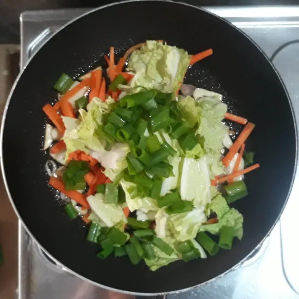 Masukkan wortel, sawi putih dan daun bawang prei. Aduk-aduk sampai sayuran layu.