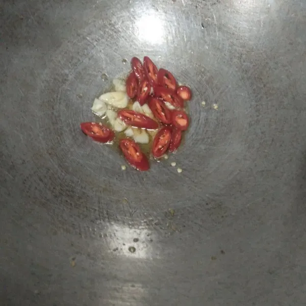 Tumis bawang putih dan cabai merah iris hingga layu dan harum, setelah itu tambahkan bumbu merah lalu aduk lagi hingga tercampur rata.