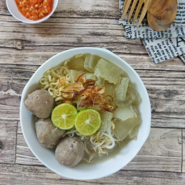 Siram kuah mie kocok yang panas, beserta kikil dan bakso secukupnya, beri bawang goreng, sambal dan air perasan jeruk limo, aduk rata lalu sajikan.