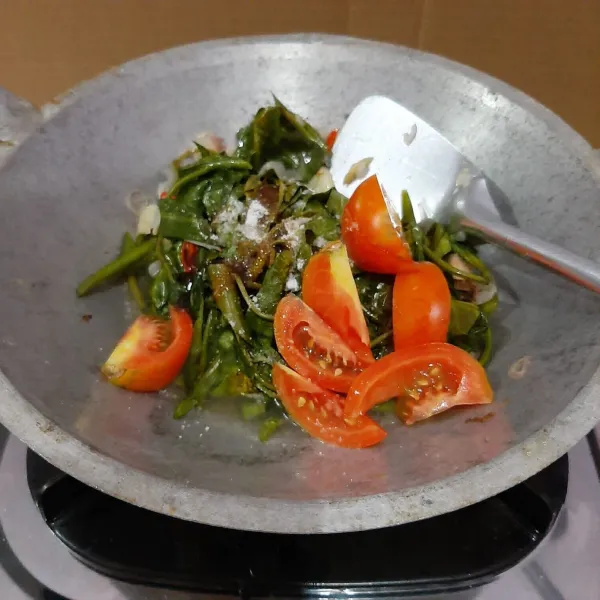 Buka wajan, tambahkan garam, penyedap, saus tiram dan kecap. Masukkan tomat. Aduk-aduk hingga semua sayuran matang.