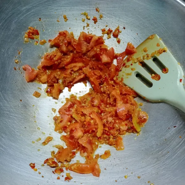 Kemudian masukkan irisan tomat, aduk rata. Masak sampai tomat layu.