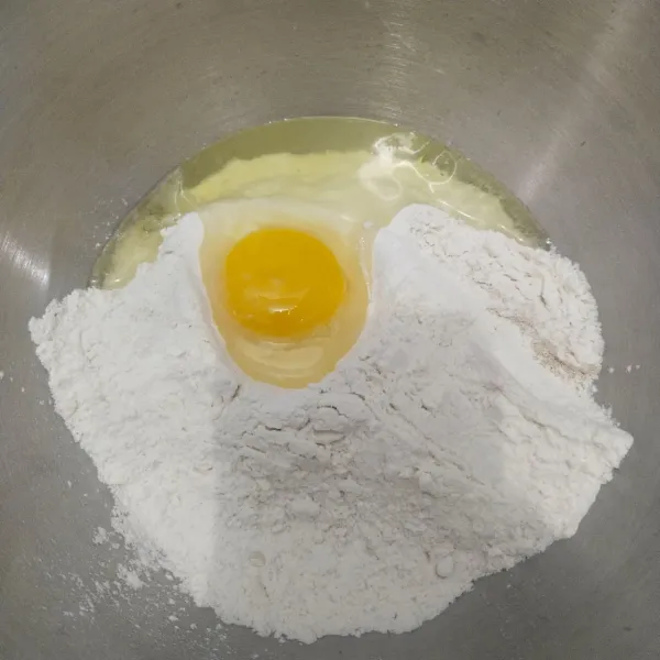 Langkah yang pertama masukkan tepung terigu, gula pasir, ragi instan, dan telur. Lalu masukkan air, uleni hingga setengah kalis.