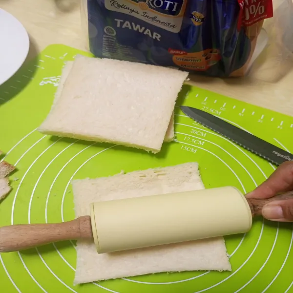 Giling tipis roti tawar menggunakan rolling pin.