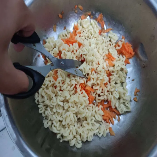 Campurkan mie dengan wortel, lalu gunting-gunting mie agar ukurannya jadi lebih kecil.