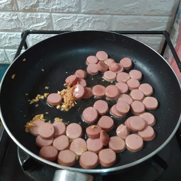 Tumis minyak dan bawang putih hingga harum. 
Masukkan sosis, tumis sebentar.