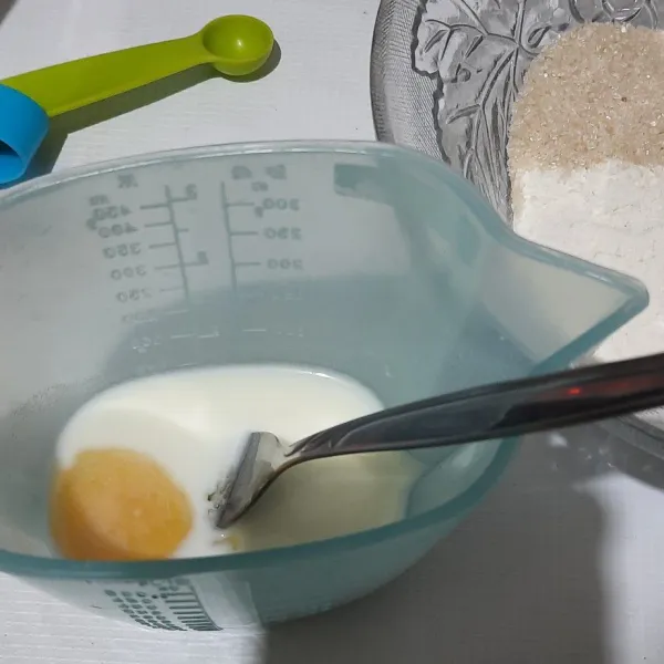 Campurkan kuning telur ke dalam susu cair, lalu aduk rata.