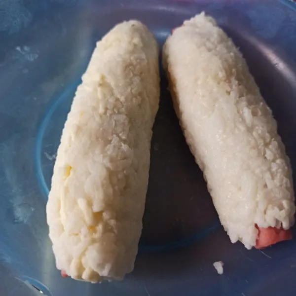 Ambil 1 buah sosis, beri keju slices lalu kepalkan nasi sampai sosis terselimuti keseluruhan.