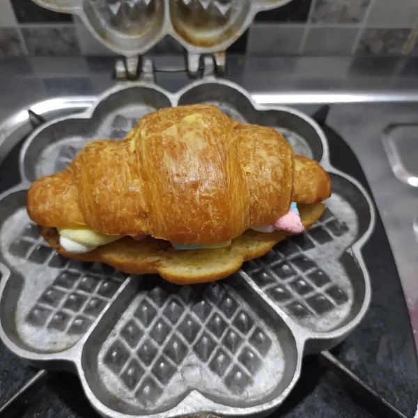 Panaskan cetakan waffle, masukkan croissant. 
Tekan cetakan sampai croissant hangat dan marshmallow meleleh.