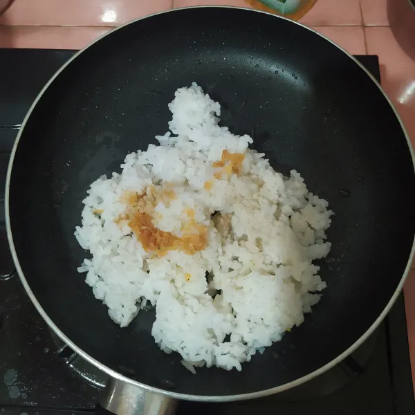Masukkan nasi ke dalam pan, beri minyak ayam bawang putih. Aduk rata.