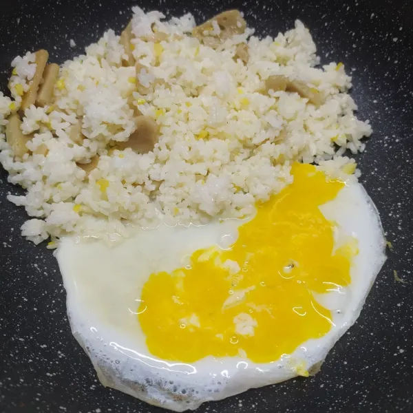 Masukkan nasi, aduk rata dengan tumisan. 
Sisihkan nasi di tepi wajan, masukkan telur. 
Bikin orak-arik telur.