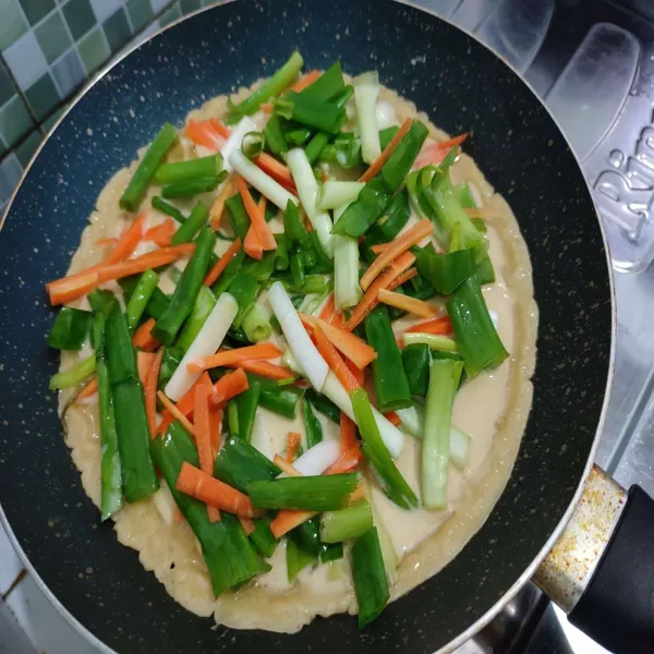 Kemudian beri daun bawang dan wortel. Masak dengan api  hingga bagian bawah nya matang, kemudian balikkan masak lagi hingga kedua sisinya matang.