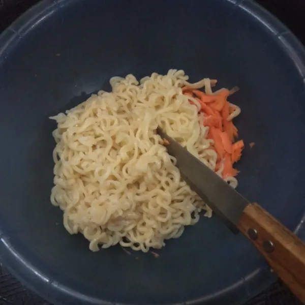 Campurkan mie dengan wortel, lalu potong-potong mie agar ukurannya jadi lebih kecil.