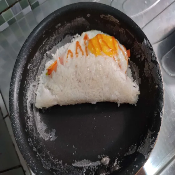 Lipat perlahan kerak nasi hingga menutupi topping.