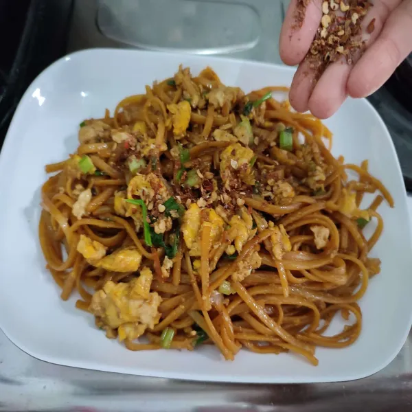 Salin Pad Thai ke piring saji, kemudian beri taburan cabai bubuk dan perasan jeruk nipis.