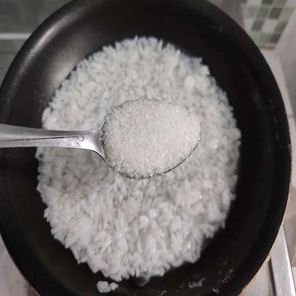 Tambahkan gula pasir, aduk rata, kemudian ratakan nasi.