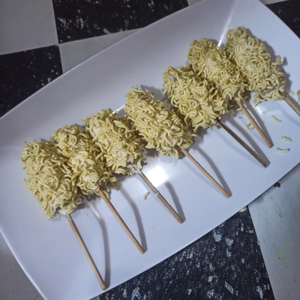 Celupkan sosis ke dalam adonan basah lalu balur dengan mie yang sudah dihancurkan.