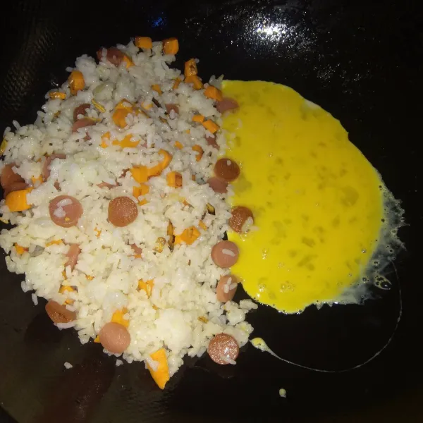 Sisihkan nasi di tepi wajan. 
Masukkan telur lalu buat telur orak-arik. 
Aduk-aduk dan orak-arik telur sampai tercampur rata dengan nasi.