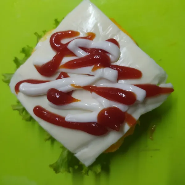 Tambahkan keju slice, beri saos tomat dan mayonaise. Lalu tutup dengan roti burger. Sajikan.